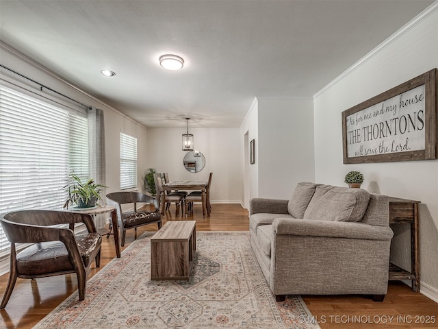 living room with light wood finished floors, crown molding, and baseboards
