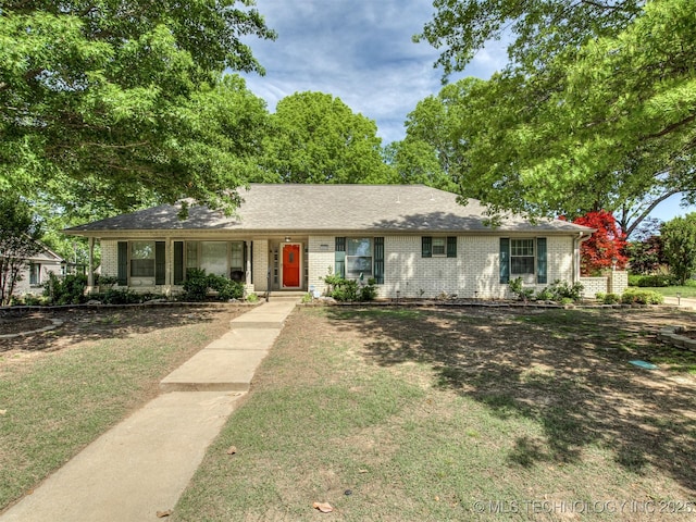 ranch-style home featuring brick siding, a front yard, and covered porch