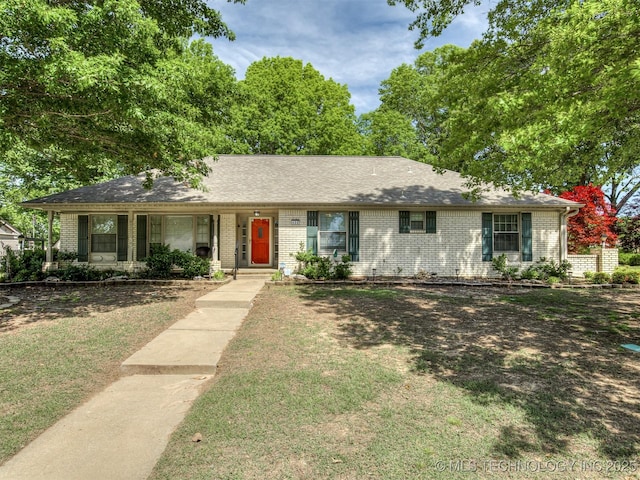 single story home with brick siding, a front yard, and a porch