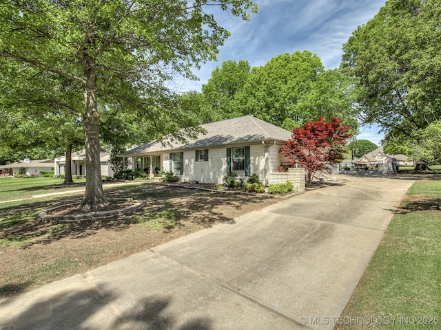 ranch-style home featuring driveway, brick siding, and roof with shingles
