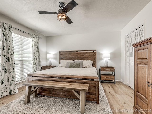 bedroom with light wood-style flooring, a textured ceiling, ceiling fan, and baseboards