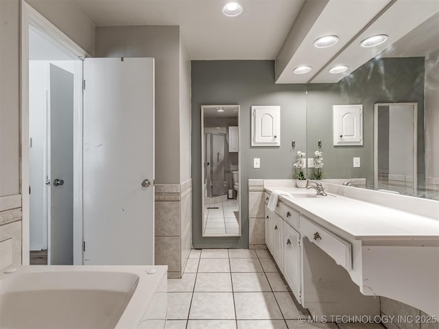 full bathroom with recessed lighting, vanity, a bath, tile walls, and tile patterned floors