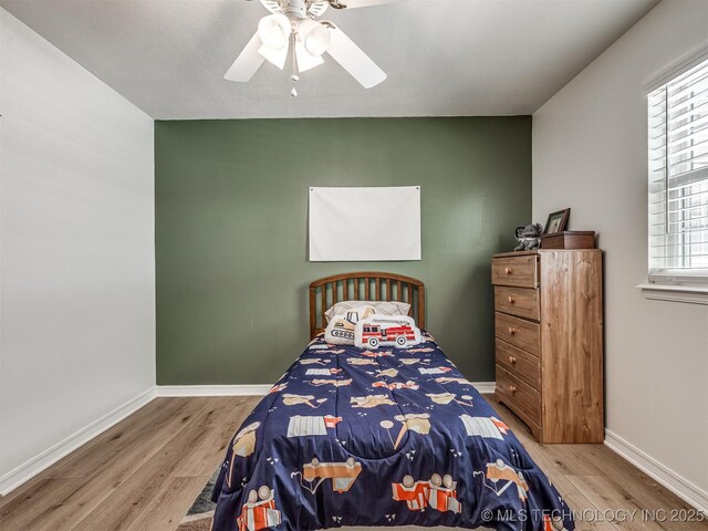 bedroom featuring wood finished floors, a ceiling fan, and baseboards