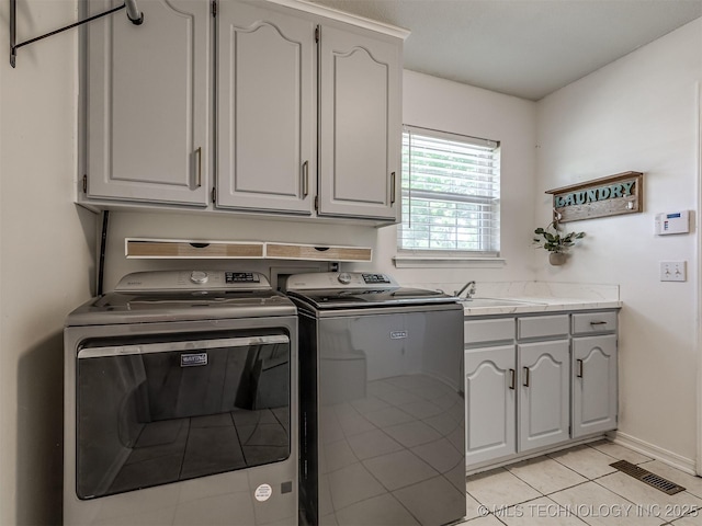 clothes washing area featuring cabinet space, washer and clothes dryer, and light tile patterned floors