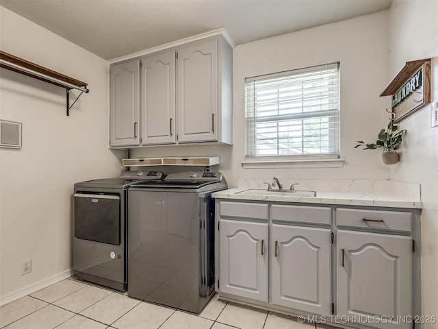 laundry area featuring cabinet space, washer and dryer, light tile patterned floors, and baseboards