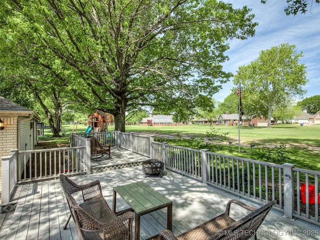wooden terrace featuring a fire pit, a playground, and a yard