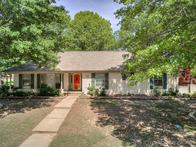 ranch-style home featuring brick siding, covered porch, and a shingled roof