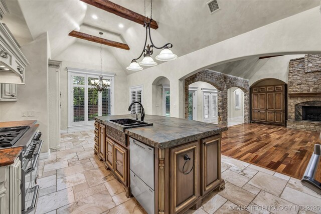 kitchen featuring stainless steel appliances, stone tile flooring, dark countertops, a sink, and high vaulted ceiling