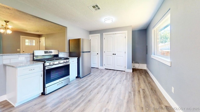 917 Fairway, Sulphur, OK 73086 - kitchen with appliances with stainless steel finishes, light wood-type flooring, white cabinetry, baseboards, and a textured ceiling