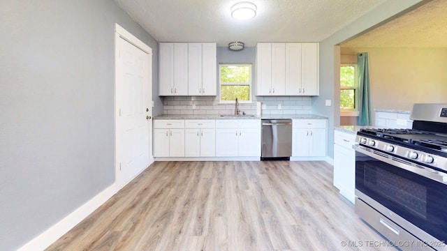 917 Fairway, Sulphur, OK 73086 - kitchen featuring appliances with stainless steel finishes, a sink, light wood-type flooring, white cabinets, and a textured ceiling