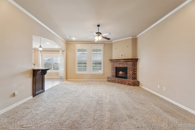 unfurnished living room with ornamental molding, ceiling fan, carpet floors, a fireplace, and baseboards