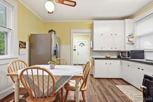 1032 E Mcleod Ave, Sapulpa, OK 74066 - kitchen featuring appliances with stainless steel finishes, light wood-style flooring, white cabinetry, crown molding, and dark countertops