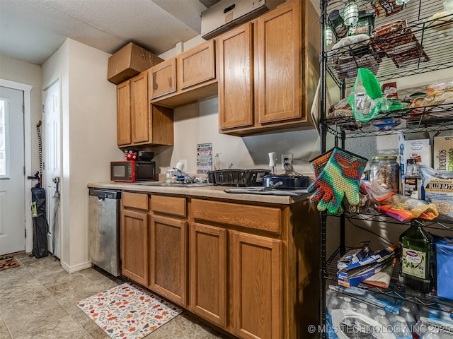 940 N Ross Ave, Dewey, OK 74029 - kitchen with stainless steel dishwasher, black microwave, light countertops, a sink, and brown cabinetry