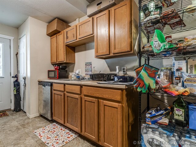 940 N Ross Ave, Dewey, OK 74029 - kitchen with stainless steel dishwasher, black microwave, light countertops, a sink, and brown cabinetry