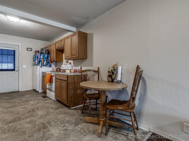 940 N Ross Ave, Dewey, OK 74029 - kitchen featuring white electric stove, brown cabinets, and baseboards