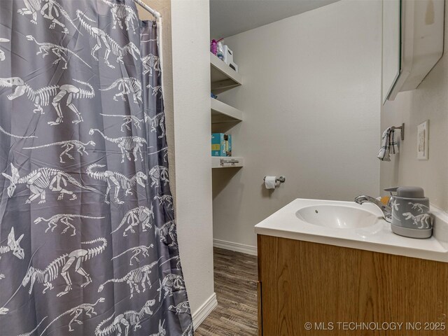 940 N Ross Ave, Dewey, OK 74029 - bathroom featuring wood finished floors, vanity, baseboards, and a shower with curtain