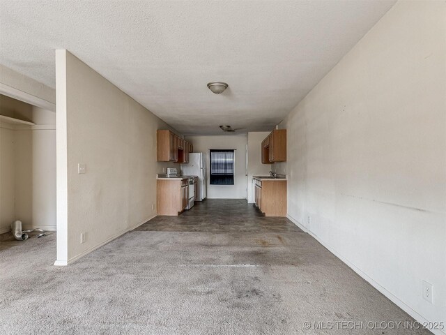 940 N Ross Ave, Dewey, OK 74029 - unfurnished living room featuring dark carpet, a textured ceiling, and baseboards
