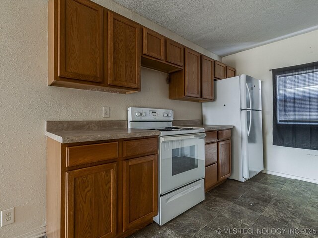 940 N Ross Ave, Dewey, OK 74029 - kitchen with white appliances, dark countertops, brown cabinets, a textured ceiling, and dark stone finish floors