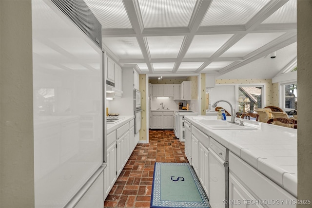 3112 Shore Dr, Grove, OK 74344 - kitchen featuring a sink, white cabinetry, coffered ceiling, brick flooring, and tile counters