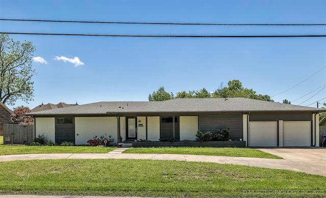 3130 E 47th St, Tulsa, OK 74105 - view of front of property featuring a garage, a front lawn, concrete driveway, and brick siding
