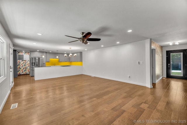 3130 E 47th St, Tulsa, OK 74105 - unfurnished living room with ceiling fan, wood finished floors, recessed lighting, baseboards, and a chandelier
