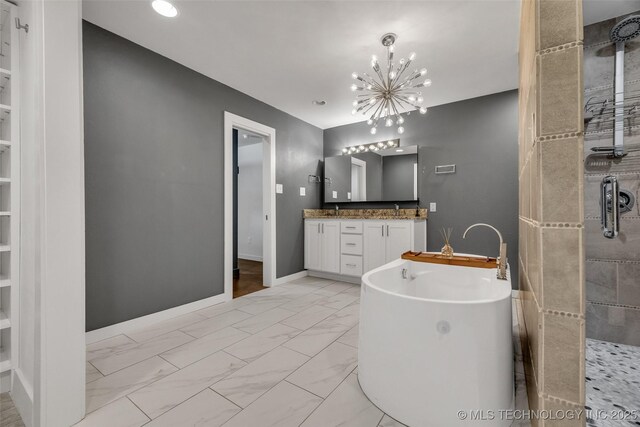 3130 E 47th St, Tulsa, OK 74105 - full bathroom with marble look tile flooring, a freestanding tub, double vanity, a chandelier, and baseboards