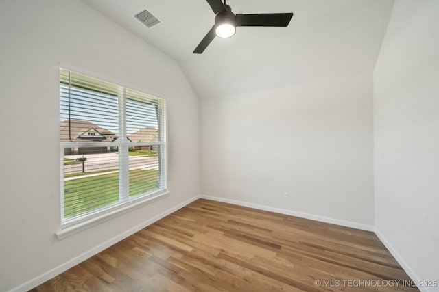 spare room featuring vaulted ceiling, wood finished floors, baseboards, and ceiling fan