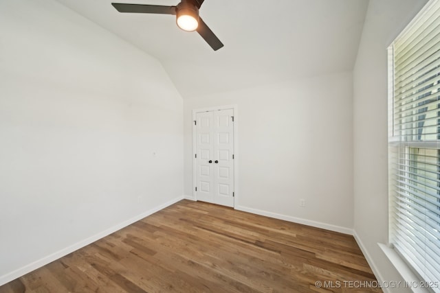 unfurnished room featuring a ceiling fan, vaulted ceiling, wood finished floors, and baseboards