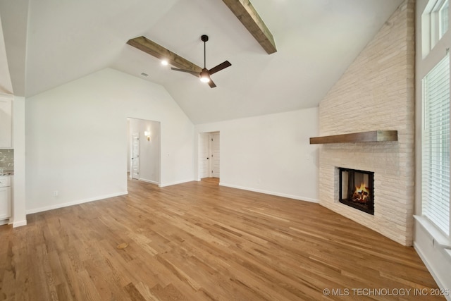 unfurnished living room featuring a ceiling fan, a brick fireplace, light wood-style flooring, high vaulted ceiling, and baseboards