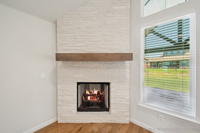 detailed view of wood finished floors, baseboards, and a fireplace