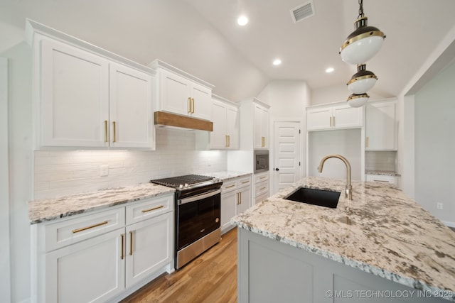 kitchen featuring a sink, appliances with stainless steel finishes, light wood-style floors, white cabinets, and lofted ceiling