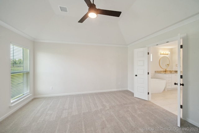 unfurnished bedroom featuring light carpet, lofted ceiling, ensuite bath, baseboards, and ceiling fan