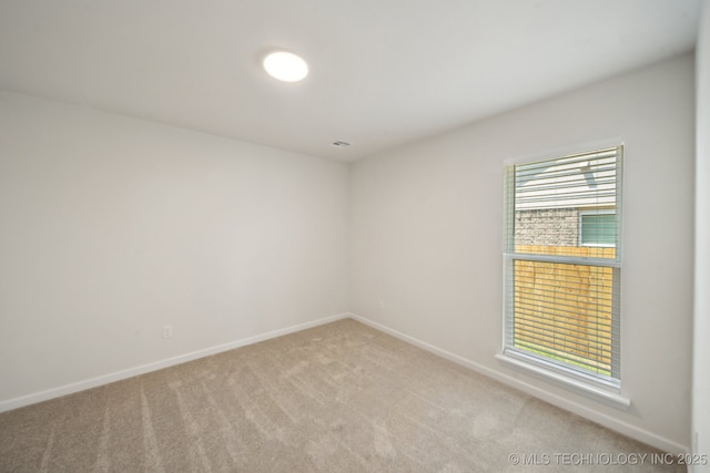spare room featuring carpet floors and baseboards