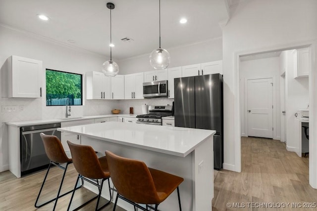 kitchen with stainless steel appliances, a sink, crown molding, tasteful backsplash, and white cabinetry