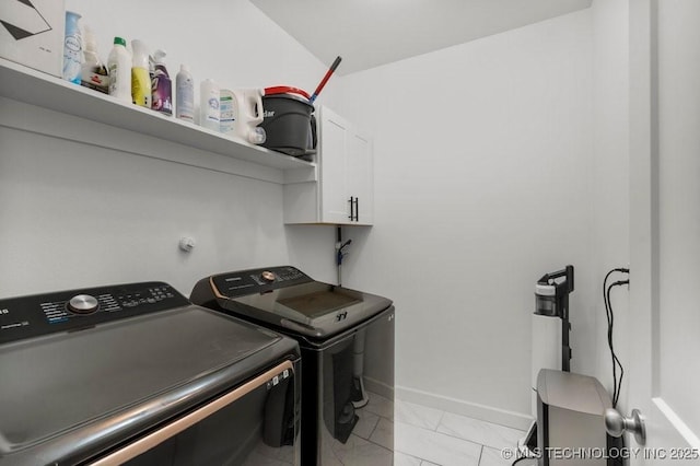 washroom featuring independent washer and dryer, cabinet space, light marble finish floors, and baseboards