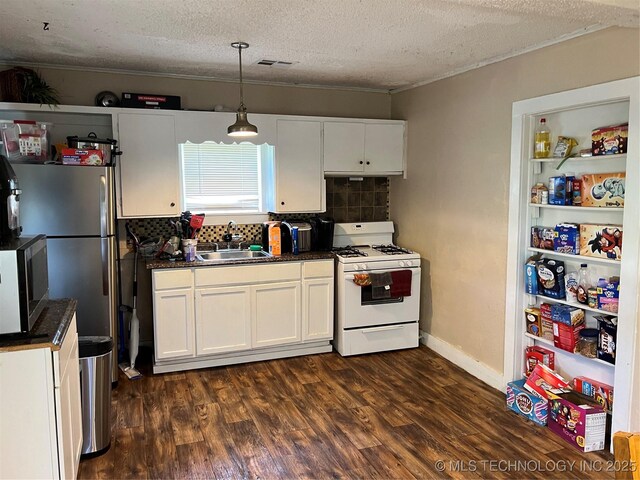 119 E Elmwood Ave, Morris, OK 74445 - kitchen featuring appliances with stainless steel finishes, dark countertops, white cabinetry, a textured ceiling, and backsplash