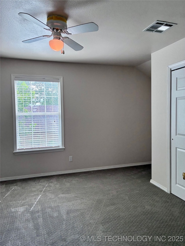 spare room with dark colored carpet, baseboards, a ceiling fan, and a textured ceiling