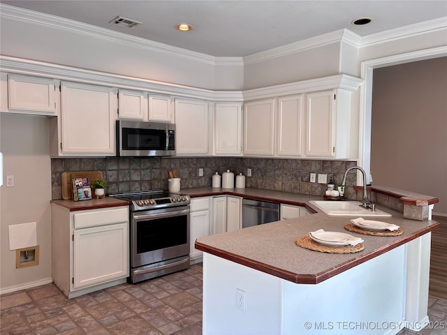 kitchen featuring stainless steel appliances, a sink, a peninsula, white cabinetry, and decorative backsplash