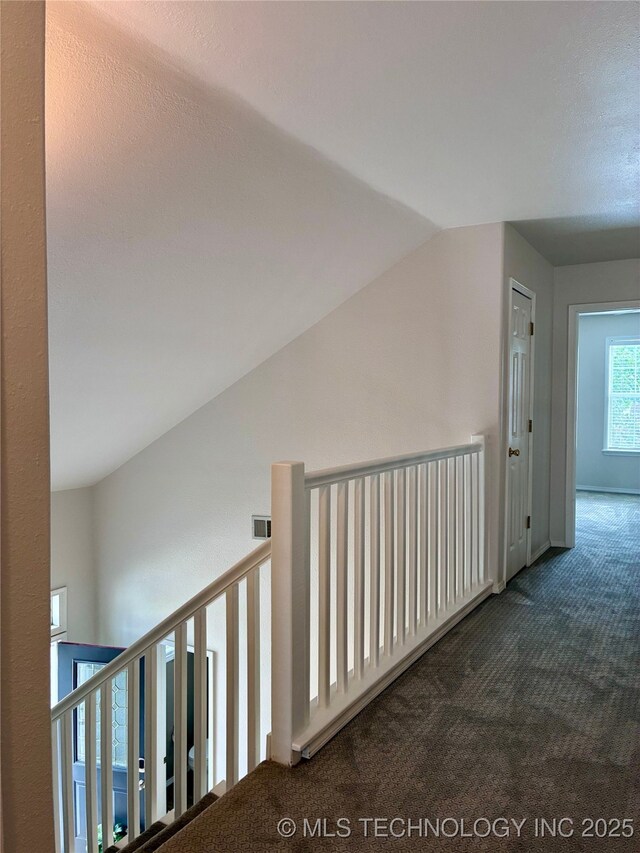 hallway with carpet, vaulted ceiling, and an upstairs landing