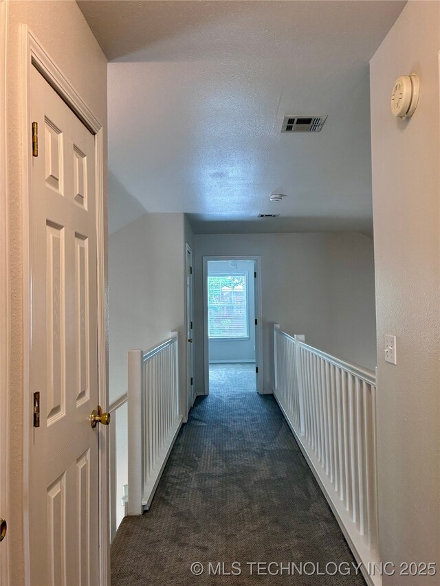 corridor with dark colored carpet and lofted ceiling