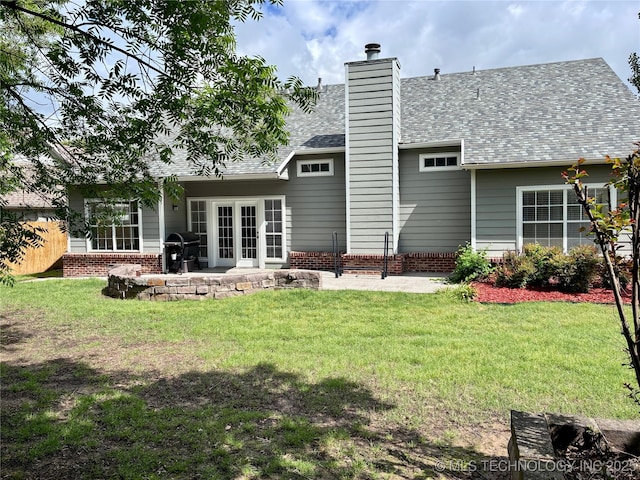 rear view of house featuring a patio, a chimney, brick siding, and a shingled roof
