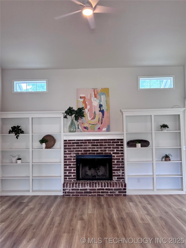 unfurnished living room featuring wood finished floors, a brick fireplace, and ceiling fan
