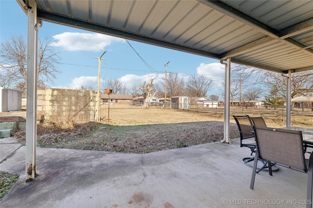view of patio featuring a storage unit, a fenced backyard, outdoor dining area, and an outbuilding
