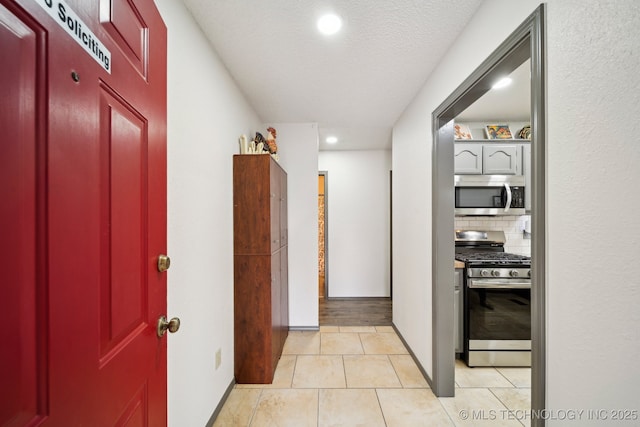 hallway featuring recessed lighting, light tile patterned floors, and a textured ceiling