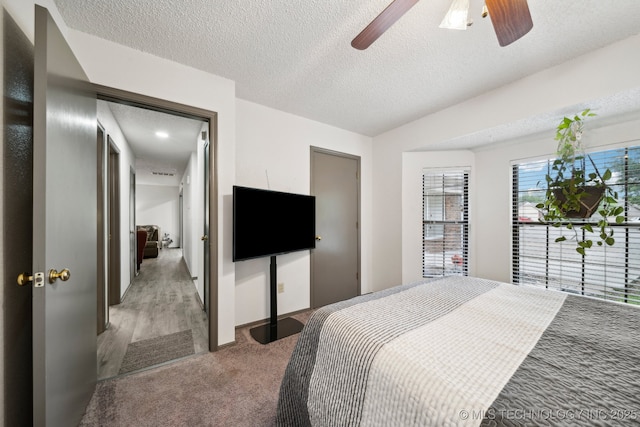 carpeted bedroom featuring a textured ceiling and ceiling fan