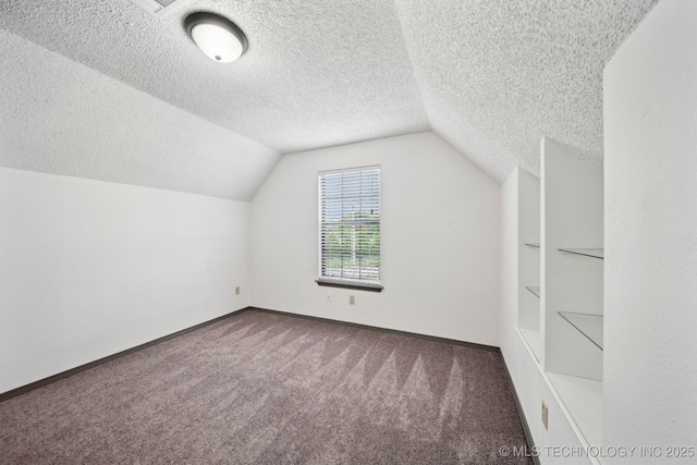 additional living space with carpet flooring, a textured ceiling, vaulted ceiling, and baseboards