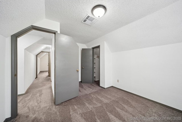bonus room featuring a textured ceiling, carpet floors, vaulted ceiling, and baseboards