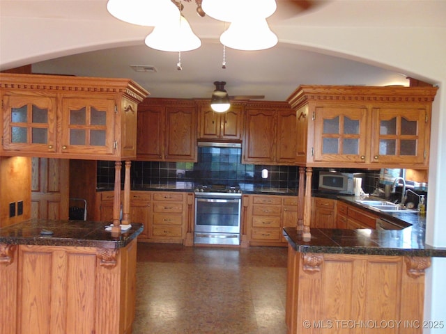 kitchen with stainless steel appliances, a peninsula, decorative backsplash, and a sink