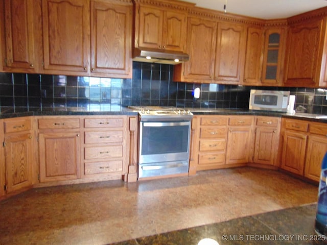 kitchen featuring stainless steel electric range, under cabinet range hood, white microwave, tasteful backsplash, and glass insert cabinets