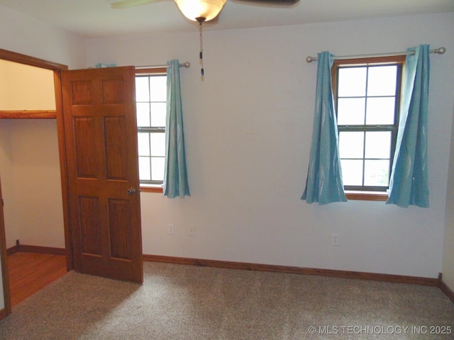 unfurnished room featuring a ceiling fan, carpet floors, and baseboards